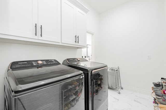 washroom featuring marble finish floor, washing machine and clothes dryer, baseboards, and cabinet space
