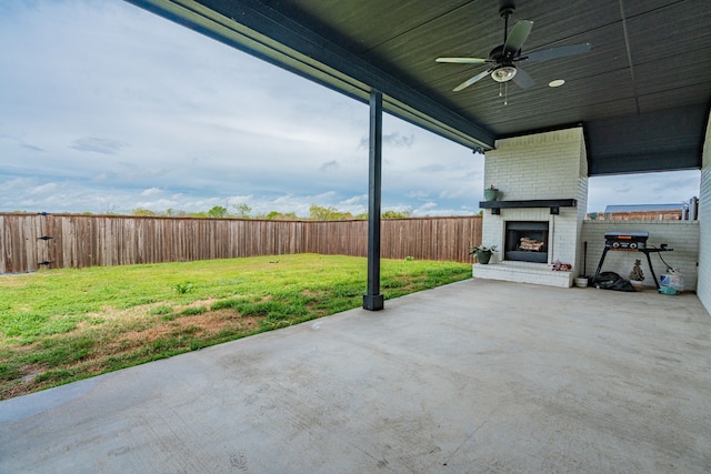 view of patio / terrace with an outdoor brick fireplace, a fenced backyard, and a ceiling fan