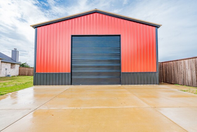detached garage featuring concrete driveway and fence