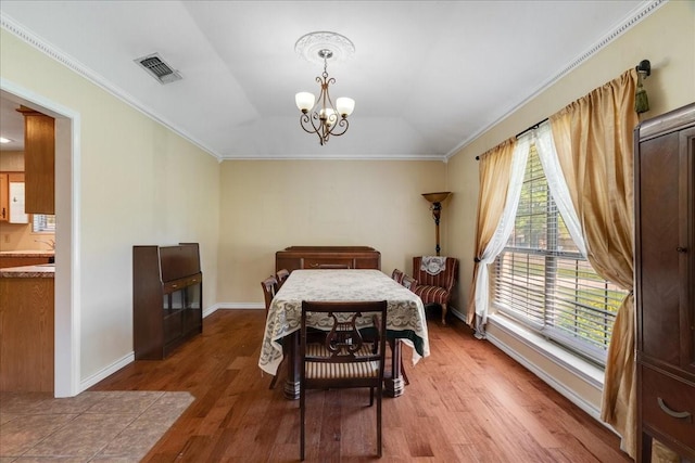 bedroom featuring baseboards, an inviting chandelier, crown molding, visible vents, and wood finished floors