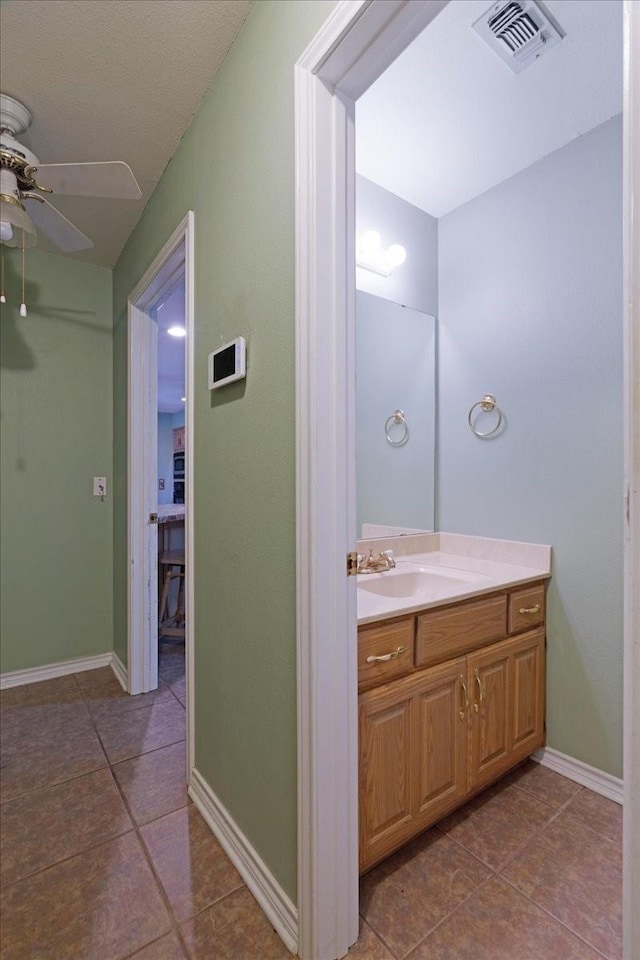 bathroom with visible vents, baseboards, a ceiling fan, vanity, and tile patterned floors