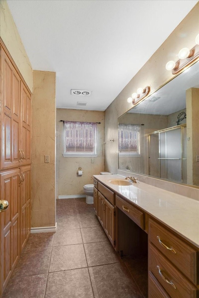 bathroom featuring visible vents, baseboards, toilet, vanity, and a stall shower
