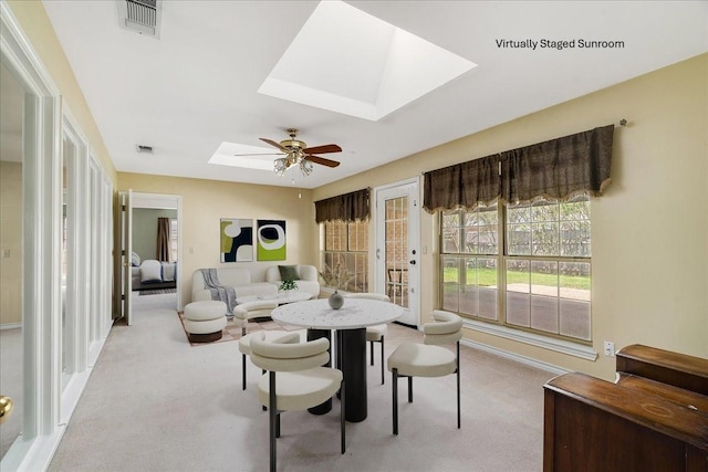interior space featuring visible vents, a skylight, a ceiling fan, and light carpet