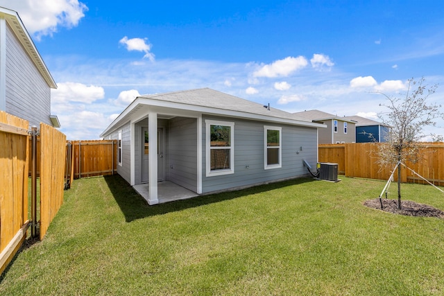 rear view of house featuring a fenced backyard and a lawn