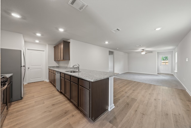 kitchen featuring visible vents, ceiling fan, stainless steel appliances, light wood finished floors, and a sink
