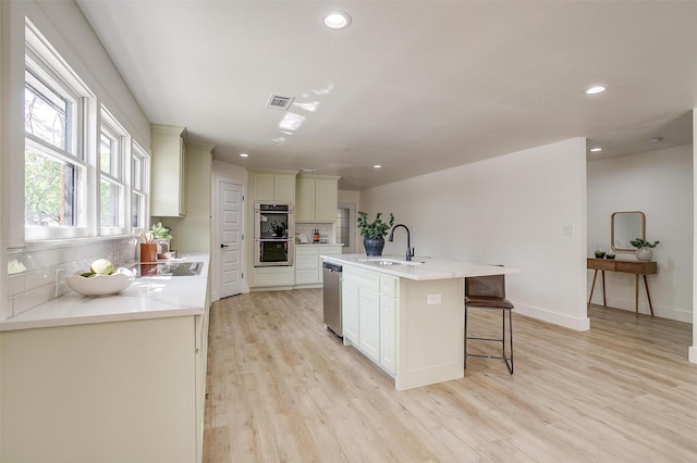 5440 Fursman Ave, Fort Worth, TX 76114 - kitchen with stainless steel appliances, backsplash, visible vents, a sink, and light wood-style floors