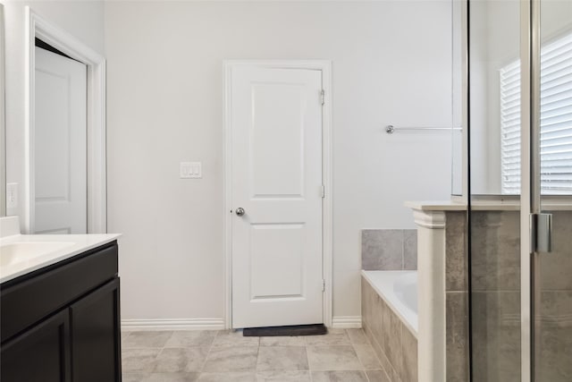 bathroom featuring baseboards, vanity, and a garden tub