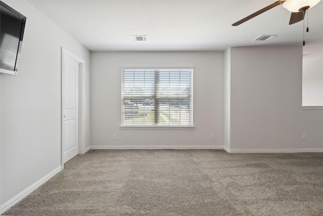 empty room with visible vents, a ceiling fan, and carpet flooring