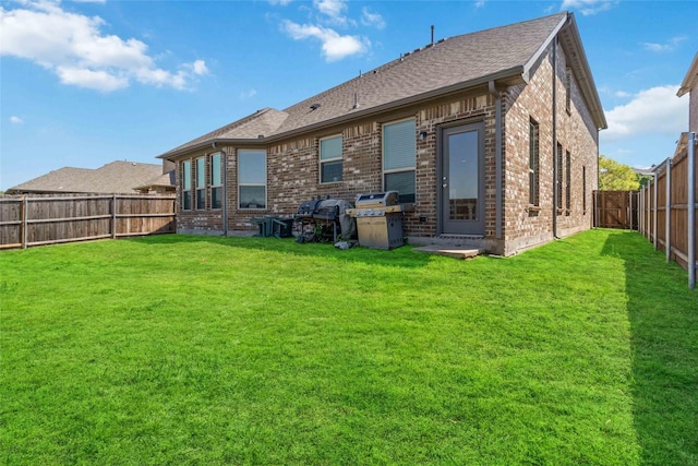 rear view of property with a yard, a fenced backyard, and brick siding