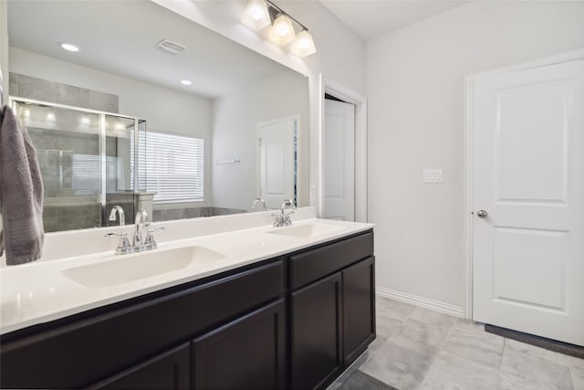 bathroom with a shower stall, double vanity, a sink, and visible vents