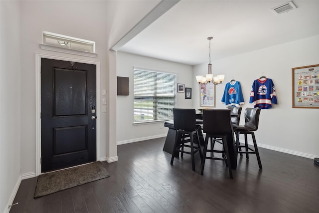 dining area featuring dark wood-type flooring, visible vents, baseboards, and an inviting chandelier