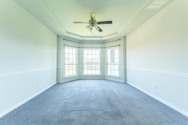 empty room featuring a tray ceiling, baseboards, a ceiling fan, and carpet