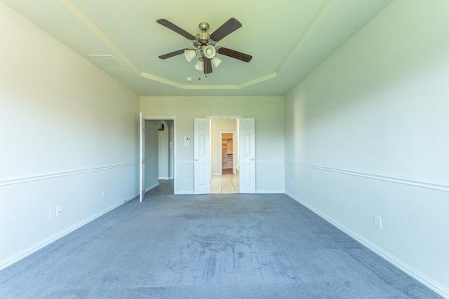 unfurnished bedroom with carpet, baseboards, a ceiling fan, and a raised ceiling