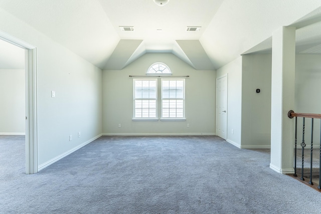 interior space with carpet flooring, visible vents, baseboards, and vaulted ceiling