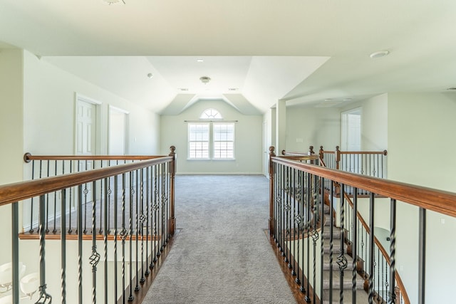 hall featuring lofted ceiling, an upstairs landing, baseboards, and carpet floors