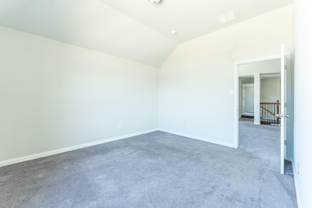 spare room featuring baseboards, carpet flooring, and vaulted ceiling