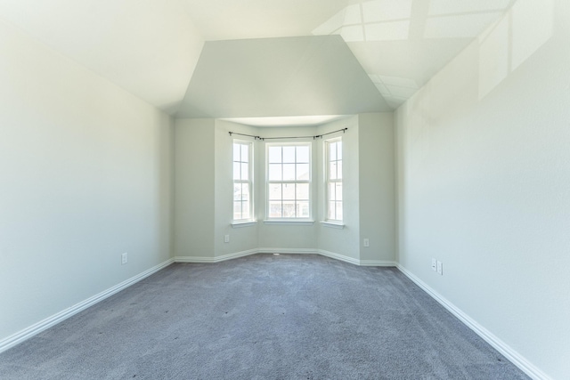 carpeted spare room with baseboards and lofted ceiling