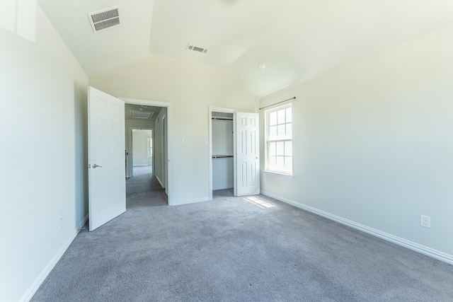 unfurnished bedroom featuring visible vents, attic access, carpet flooring, and vaulted ceiling