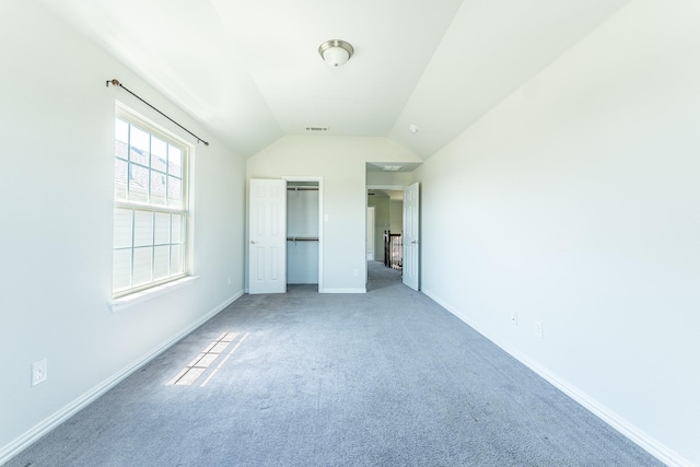 unfurnished bedroom featuring a closet, baseboards, visible vents, lofted ceiling, and carpet