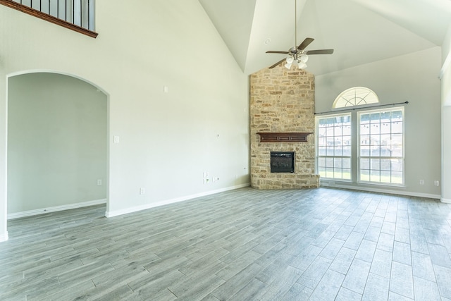 unfurnished living room with baseboards, high vaulted ceiling, wood finished floors, and a ceiling fan