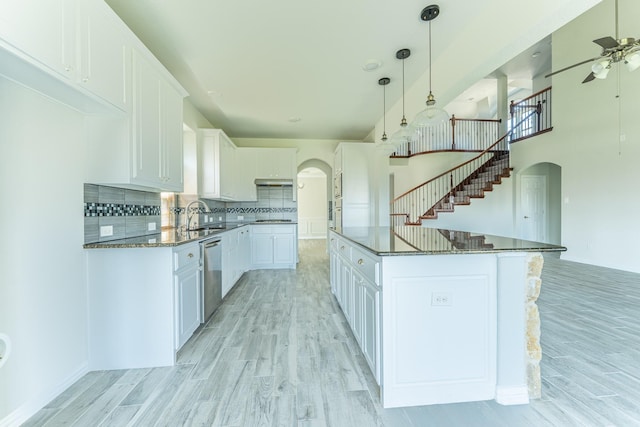 kitchen featuring tasteful backsplash, arched walkways, dishwasher, ceiling fan, and light wood-style floors