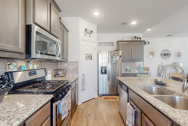 2821 Journey Ln, Forney, TX 75126 - kitchen featuring stainless steel appliances, a sink, light wood-type flooring, backsplash, and light stone countertops