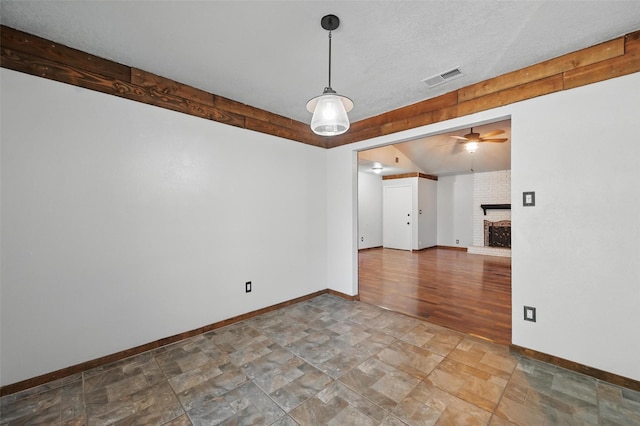 2306 Lavon Creek Ln, Arlington, TX 76006 - spare room with baseboards, visible vents, a brick fireplace, ceiling fan, and stone finish flooring