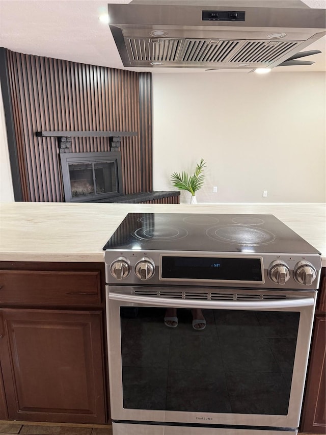 5540 Rutledge Dr, The Colony, TX 75056 - kitchen with light countertops, range hood, electric range, and a fireplace