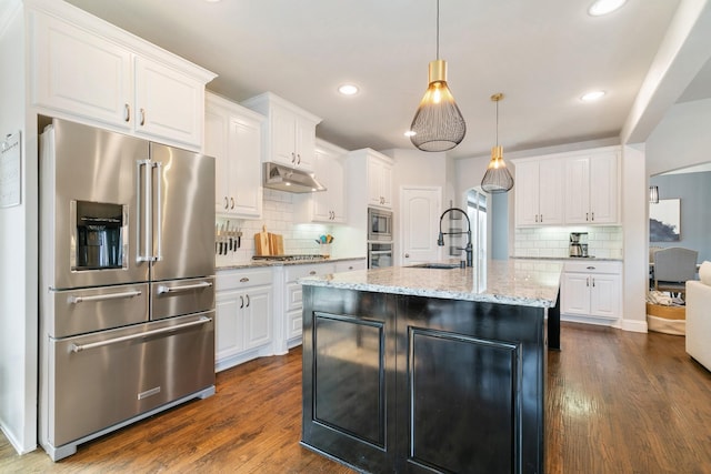 kitchen with tasteful backsplash, stainless steel appliances, under cabinet range hood, a sink, and white cabinetry