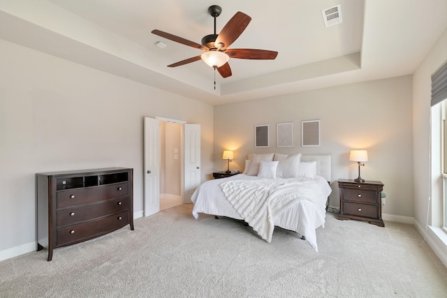 bedroom with visible vents, ceiling fan, a tray ceiling, and carpet floors