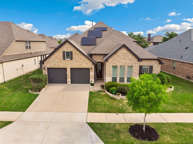 745 Sandbox Dr, Little Elm, TX 76227 - french country inspired facade featuring brick siding, roof with shingles, concrete driveway, and solar panels