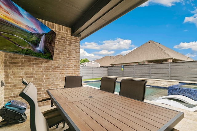 view of patio with a fenced in pool, outdoor dining space, an in ground hot tub, and a fenced backyard