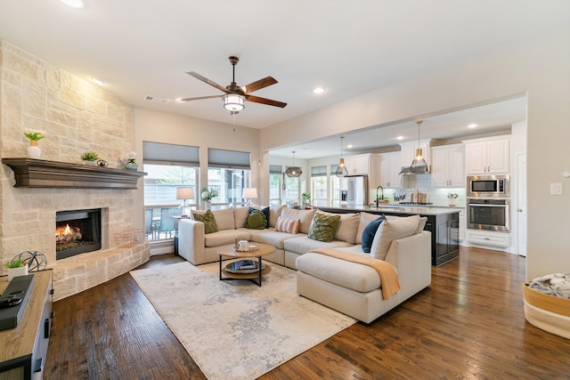 living room featuring recessed lighting, dark wood-style flooring, a fireplace, ceiling fan, and visible vents