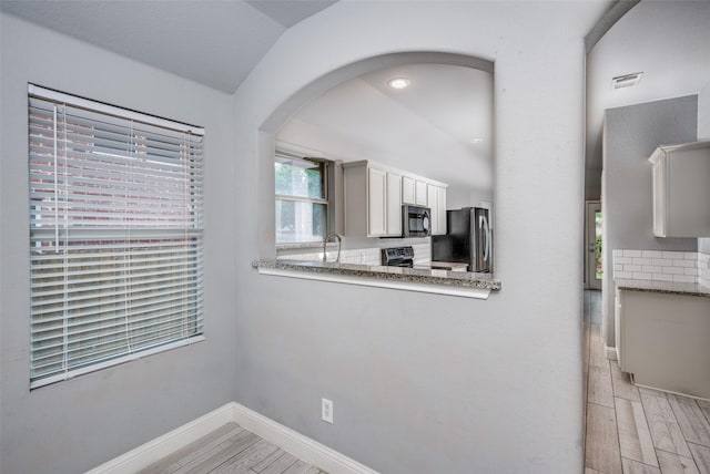 kitchen with visible vents, appliances with stainless steel finishes, baseboards, light wood-style floors, and white cabinetry