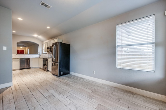 kitchen with visible vents, white cabinetry, arched walkways, backsplash, and stainless steel appliances