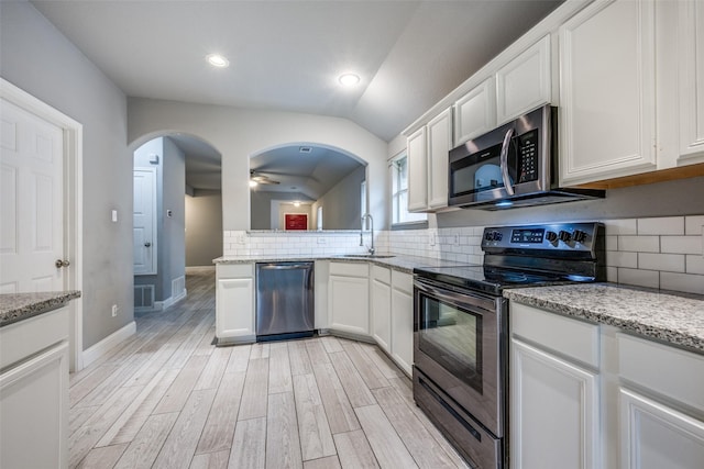 kitchen featuring a sink, decorative backsplash, appliances with stainless steel finishes, and arched walkways