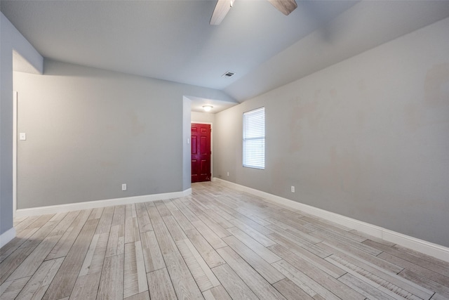 unfurnished room with ceiling fan, visible vents, vaulted ceiling, baseboards, and light wood-style flooring
