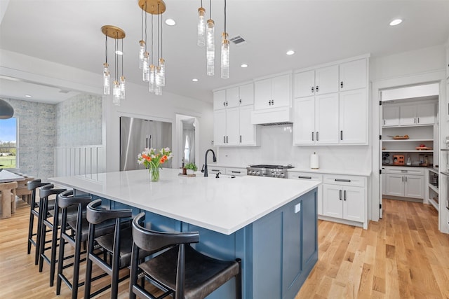 kitchen with white cabinetry, high end refrigerator, light wood-type flooring, and range