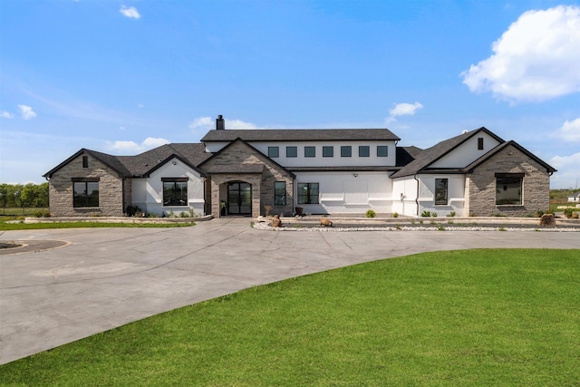 view of front of home featuring roof with shingles, stone siding, a front lawn, and stucco siding