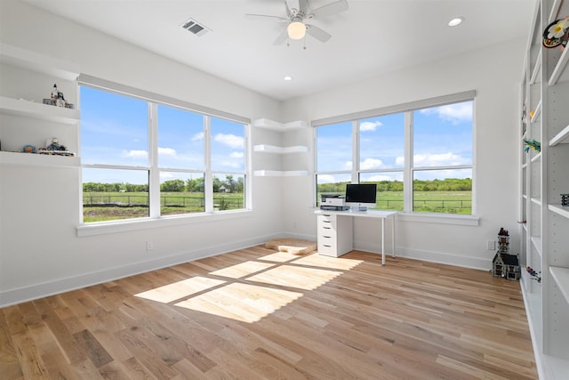 spare room with ceiling fan, a healthy amount of sunlight, light wood-style flooring, baseboards, and visible vents
