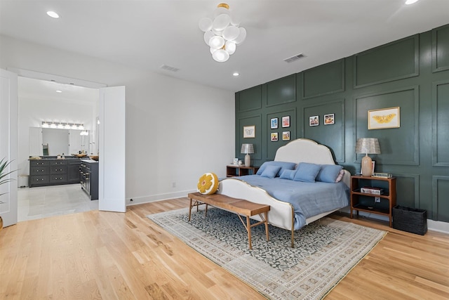 bedroom with recessed lighting, light wood-style floors, a decorative wall, and visible vents
