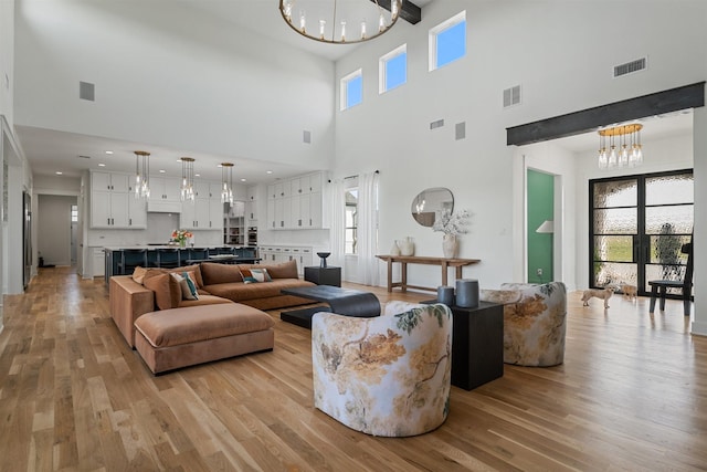 living room with a notable chandelier, a towering ceiling, and visible vents