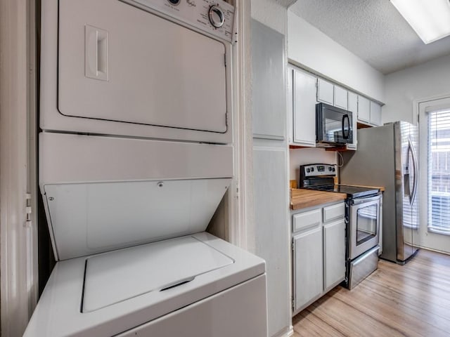 laundry room with light wood finished floors, stacked washing maching and dryer, laundry area, and a textured ceiling