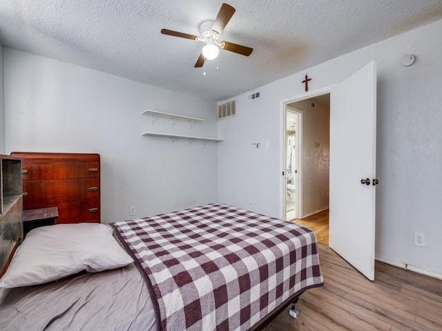 bedroom with visible vents, a ceiling fan, wood finished floors, and a textured ceiling