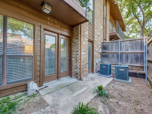 exterior space featuring brick siding, central AC, and fence