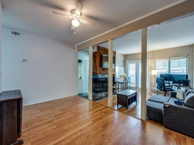 living room with light wood-style flooring, a textured ceiling, and a ceiling fan