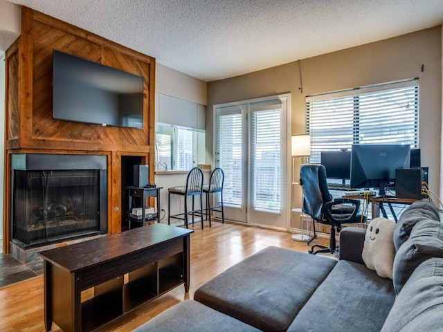 living area featuring a textured ceiling, wood finished floors, and a fireplace