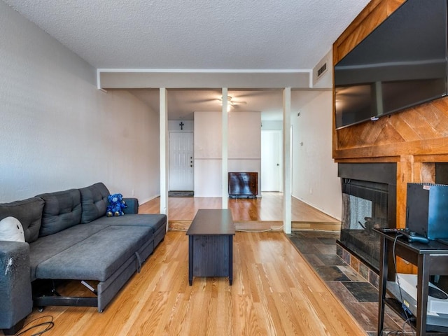 living area featuring visible vents, a multi sided fireplace, wood finished floors, and a textured ceiling