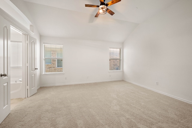 unfurnished bedroom featuring light colored carpet, multiple windows, and vaulted ceiling