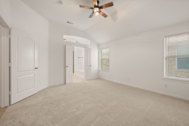 unfurnished bedroom featuring baseboards, connected bathroom, visible vents, lofted ceiling, and light colored carpet